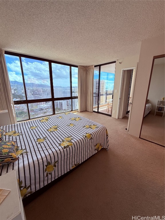 carpeted bedroom with a water view, a textured ceiling, and multiple windows