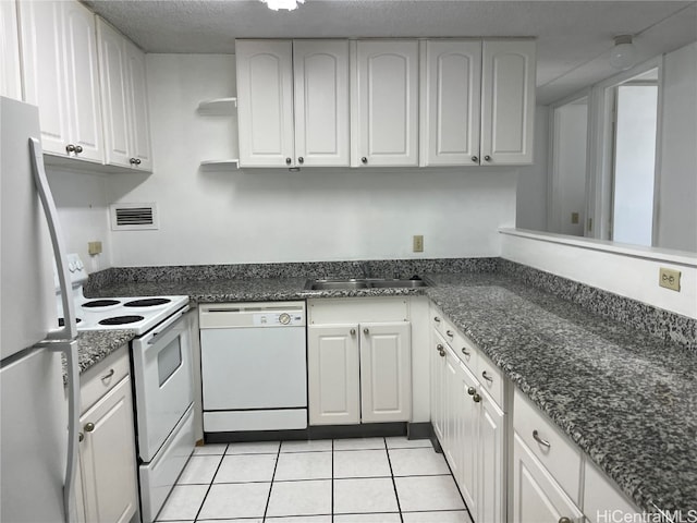 kitchen featuring sink, light tile patterned flooring, white cabinets, a textured ceiling, and white appliances