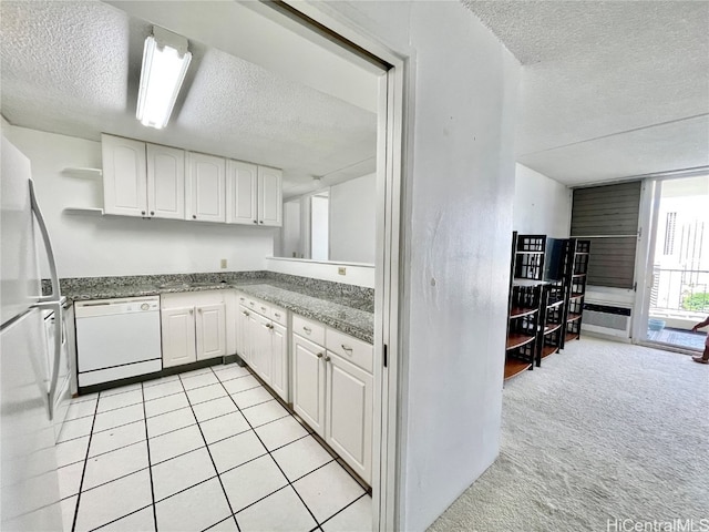 kitchen with white cabinets, light carpet, a textured ceiling, and white appliances