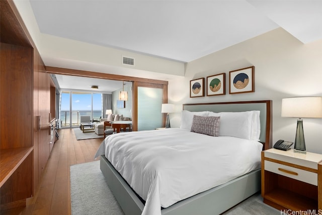 bedroom featuring a water view and light hardwood / wood-style floors