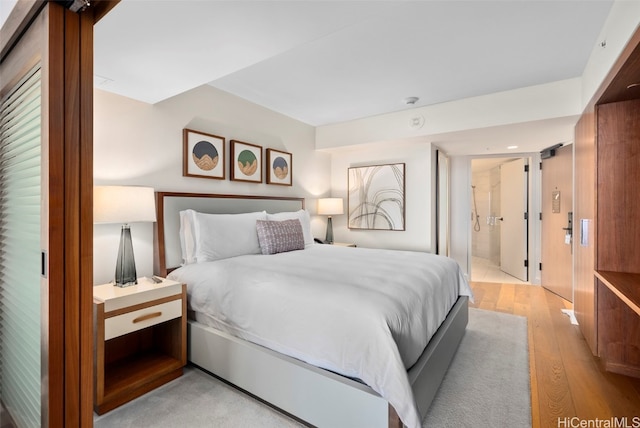 bedroom featuring connected bathroom and light hardwood / wood-style flooring