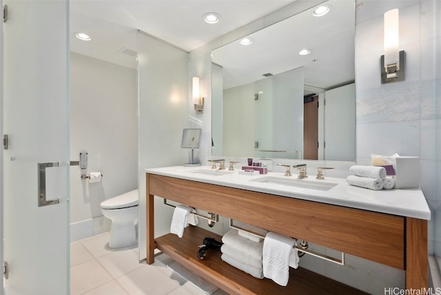 bathroom with toilet, vanity, and tile patterned flooring