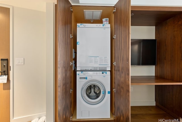 laundry area featuring stacked washer and clothes dryer and wood-type flooring