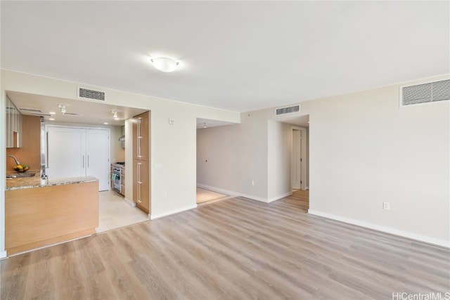 unfurnished living room with sink and light wood-type flooring