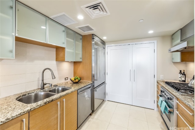 kitchen with sink, light stone counters, stainless steel appliances, and backsplash