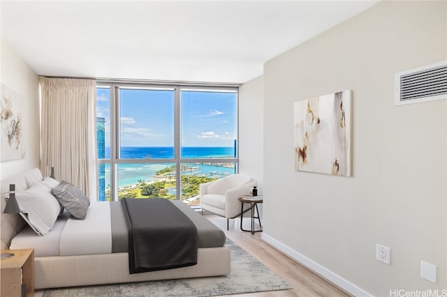 bedroom with a water view, hardwood / wood-style flooring, and multiple windows