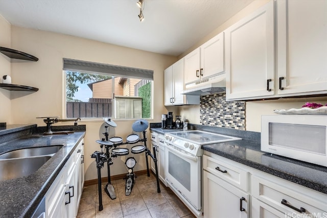 kitchen with tasteful backsplash, white appliances, sink, light tile patterned floors, and white cabinets