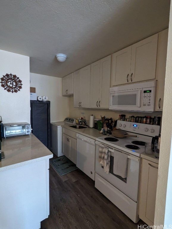 kitchen with washer / dryer, white cabinetry, dark wood-type flooring, sink, and white appliances