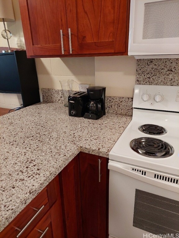 kitchen with electric stove and light stone countertops