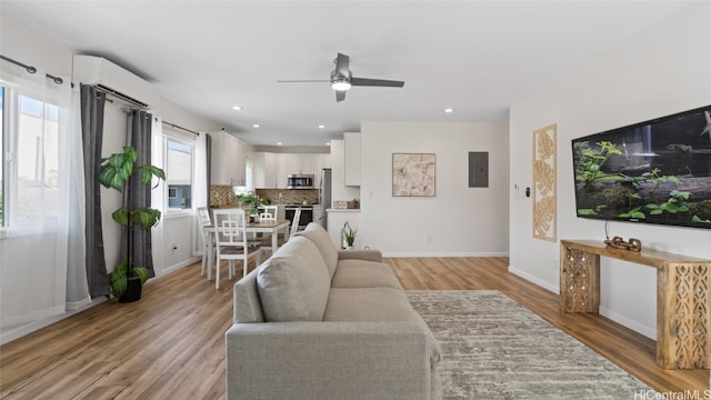 living room featuring ceiling fan, electric panel, and light hardwood / wood-style flooring