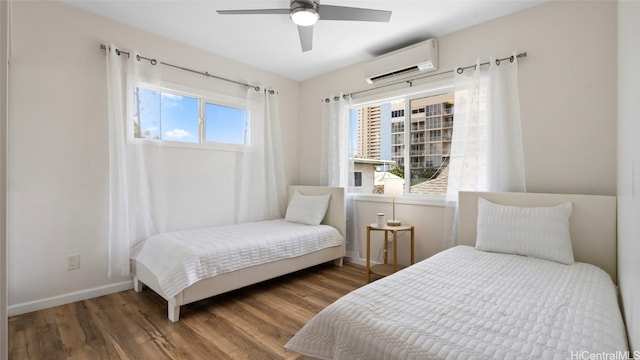 bedroom featuring multiple windows, a wall mounted AC, wood-type flooring, and ceiling fan