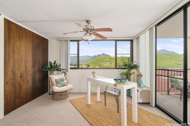 office space with a mountain view, ceiling fan, light colored carpet, and a textured ceiling