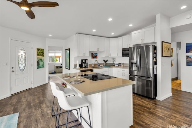 kitchen with white cabinets, appliances with stainless steel finishes, a kitchen bar, dark hardwood / wood-style floors, and a center island