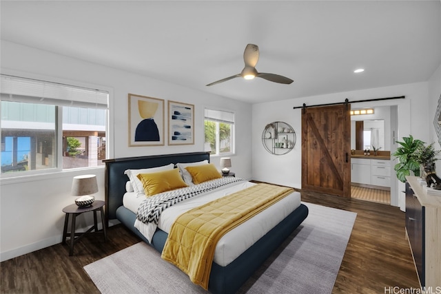 bedroom with connected bathroom, ceiling fan, dark hardwood / wood-style floors, and a barn door