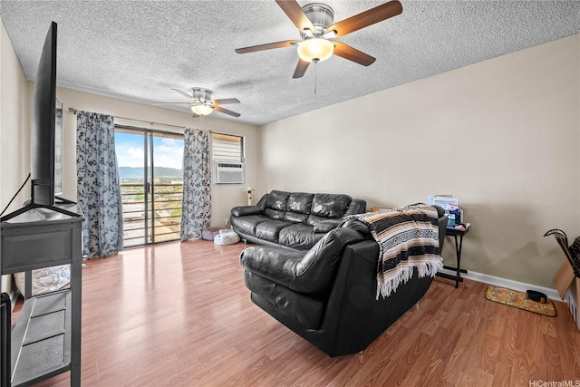 living room with cooling unit, a textured ceiling, wood-type flooring, and ceiling fan