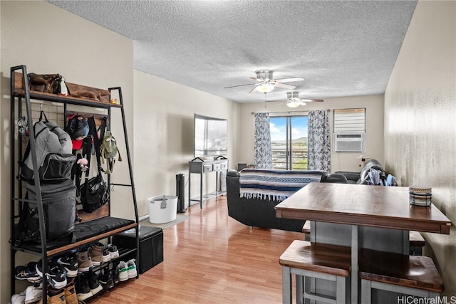 dining area featuring light hardwood / wood-style floors, cooling unit, a textured ceiling, and ceiling fan