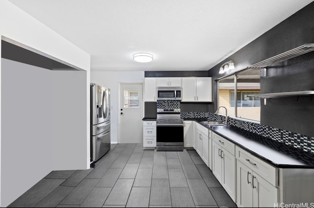 kitchen featuring backsplash, sink, appliances with stainless steel finishes, and white cabinets