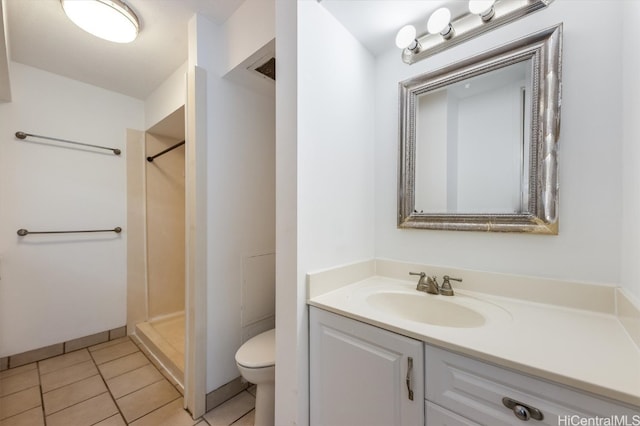 bathroom with vanity, a shower, toilet, and tile patterned flooring