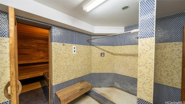 bathroom with walk in shower and tile walls