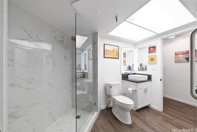 bathroom featuring a shower with door, vanity, wood-type flooring, and toilet