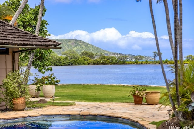 view of swimming pool with a patio, a water and mountain view, a lawn, and a jacuzzi