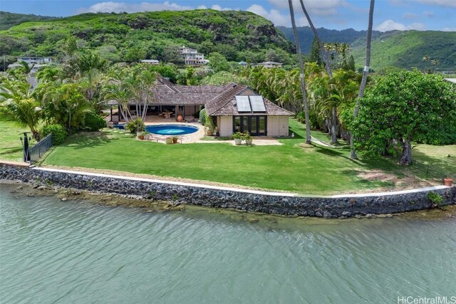 rear view of property with a yard, a water and mountain view, and an in ground hot tub