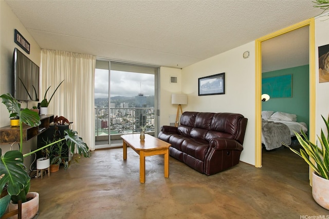 living room featuring a textured ceiling, visible vents, finished concrete floors, and expansive windows