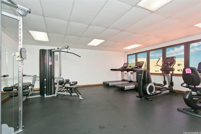 exercise room with a drop ceiling and baseboards