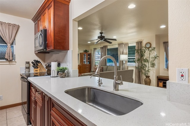 kitchen featuring light stone countertops, sink, ceiling fan, stainless steel appliances, and light tile patterned floors