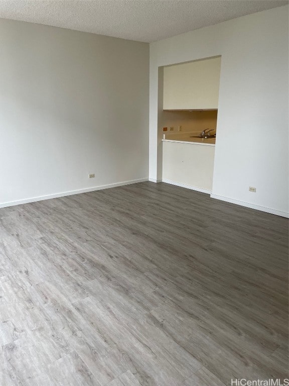 spare room featuring dark wood-type flooring, a textured ceiling, and sink