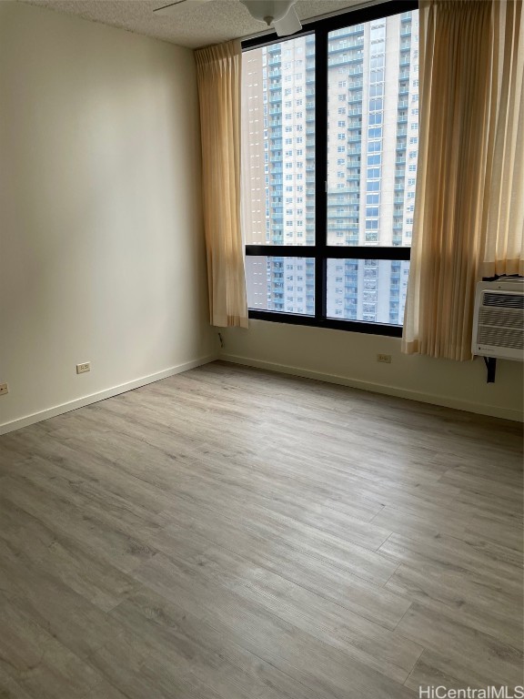 spare room with cooling unit, a textured ceiling, and hardwood / wood-style floors