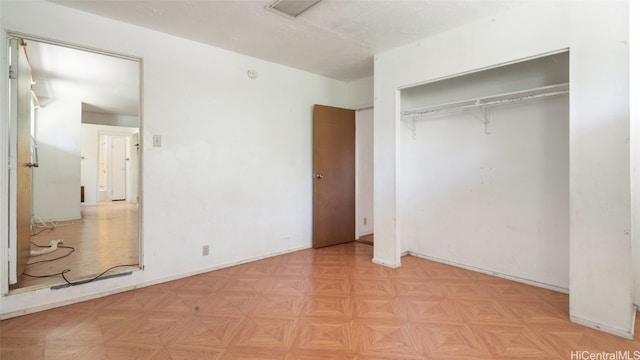 unfurnished bedroom featuring light parquet flooring and a closet