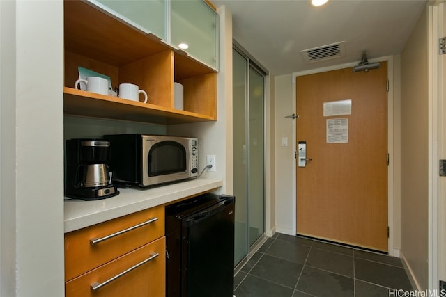 kitchen with black refrigerator and dark tile patterned flooring