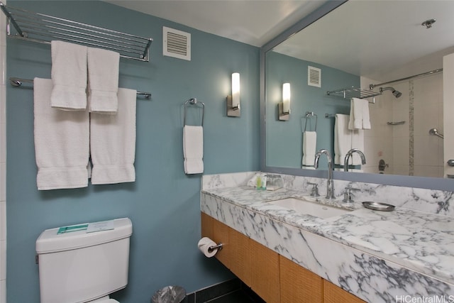 bathroom featuring vanity, toilet, and a tile shower