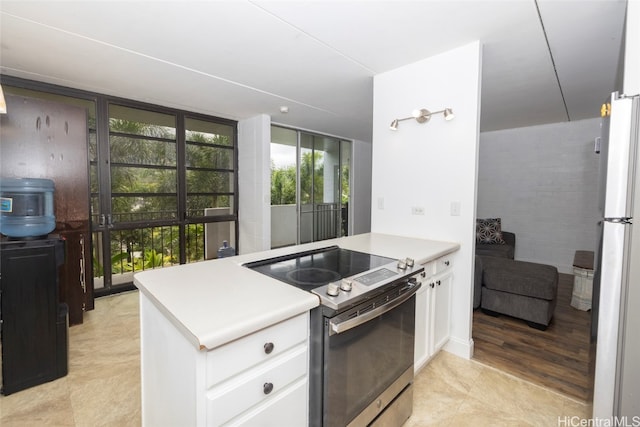 kitchen with white fridge, white cabinets, stainless steel electric range, and kitchen peninsula