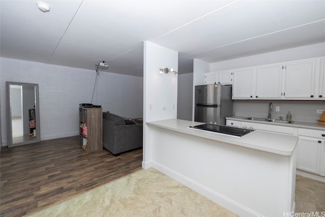 kitchen featuring kitchen peninsula, sink, hardwood / wood-style floors, white cabinets, and stainless steel refrigerator