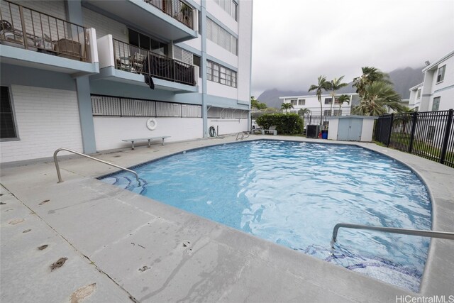 view of pool featuring a shed and a patio area