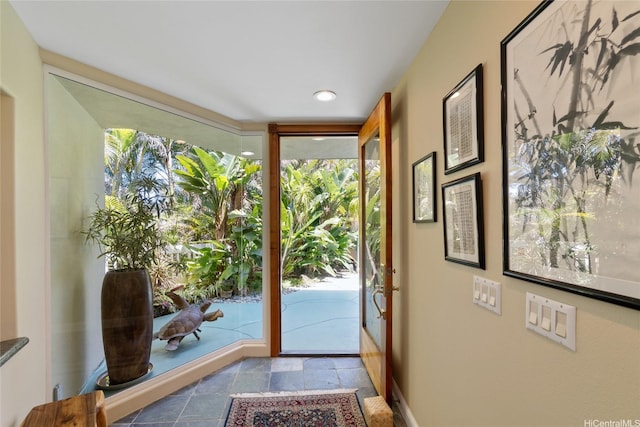 doorway featuring stone tile floors and baseboards