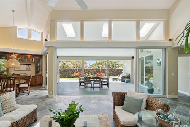 living area with baseboards, a towering ceiling, and a skylight