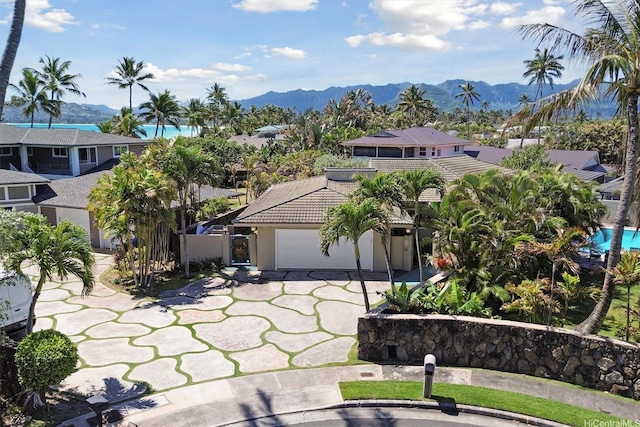 view of front of house with a tile roof, a mountain view, concrete driveway, an attached garage, and stucco siding