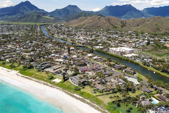 drone / aerial view with a water and mountain view and a view of the beach