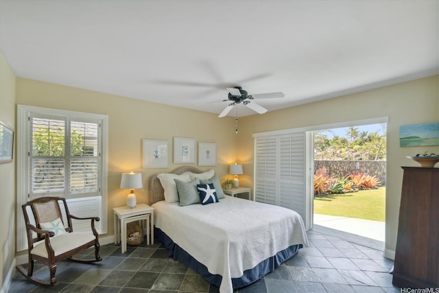 bedroom with baseboards, access to outside, ceiling fan, and stone finish flooring