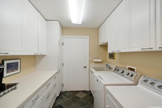 clothes washing area featuring cabinet space, independent washer and dryer, stone finish flooring, and a sink