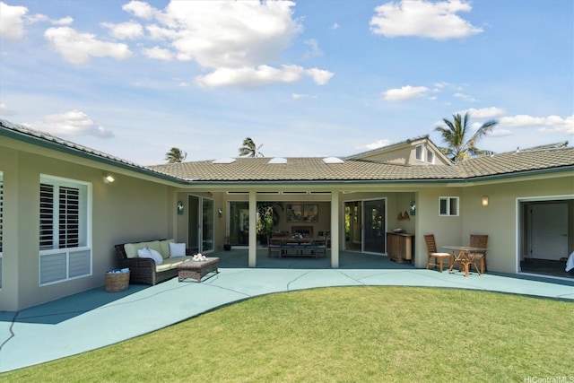 rear view of property with stucco siding, a patio area, a tile roof, an outdoor living space, and a lawn