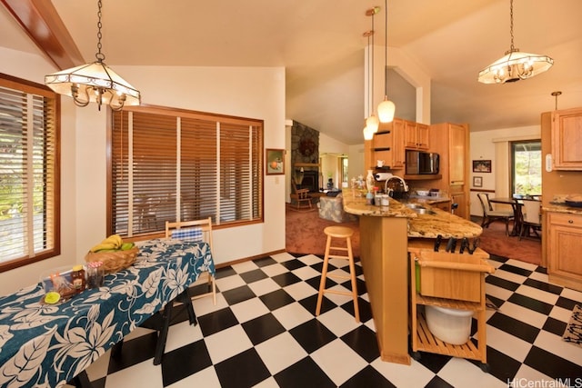 kitchen featuring sink, kitchen peninsula, hanging light fixtures, a kitchen breakfast bar, and vaulted ceiling