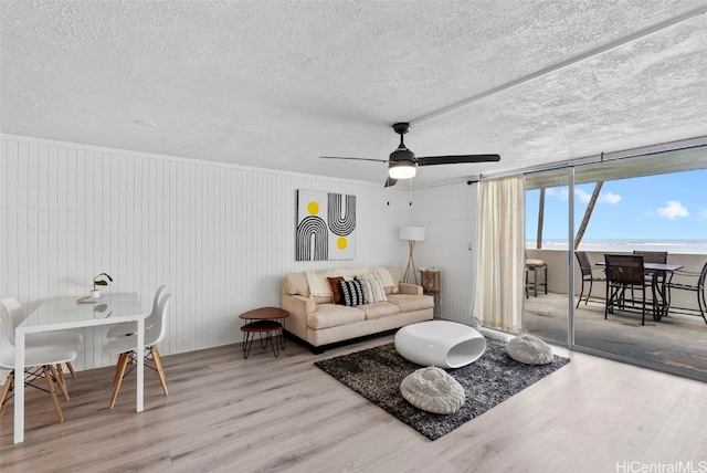 living room with ceiling fan, wood-type flooring, and a textured ceiling