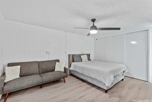 bedroom with light hardwood / wood-style floors, a textured ceiling, and ceiling fan