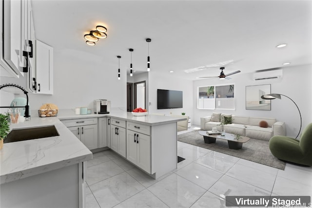 kitchen featuring kitchen peninsula, hanging light fixtures, white cabinetry, a wall mounted air conditioner, and sink