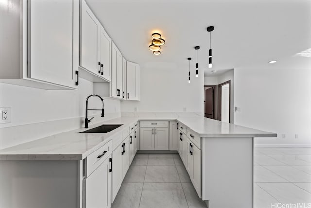 kitchen featuring light stone countertops, sink, kitchen peninsula, hanging light fixtures, and white cabinets