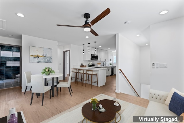 living room featuring sink, light wood-type flooring, and ceiling fan